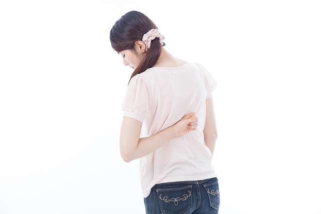 背中の張りに悩む女性